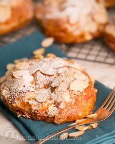 a muffin with powdered sugar on top sitting on a blue napkin next to a fork