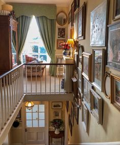 a staircase with pictures on the wall and framed photos on the wall above it, leading to a living room