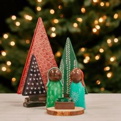 three small wooden christmas trees sitting on top of a table next to a christmas tree