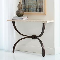 a table with a vase on top of it next to a painting and some books