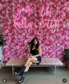 a woman is sitting on a bench in front of a wall with pink flowers and the words you're like pretty