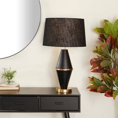 a table with a lamp and mirror on it next to a potted green plant