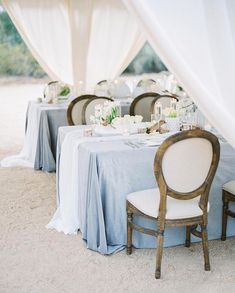 a table set up with white linens and candles