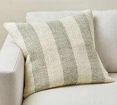 a white couch with a striped pillow sitting on it's backrest and arm