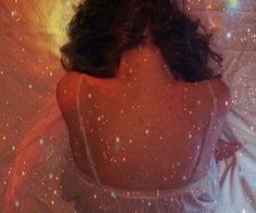 a woman laying in bed with her back turned to the camera and stars all around