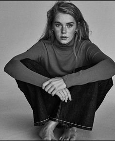 a black and white photo of a woman sitting on the ground with her legs crossed