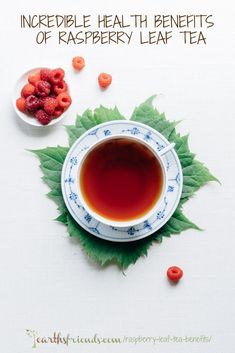 a cup of tea with raspberries next to it