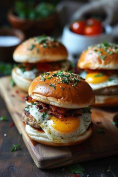 eggs, bacon and cheese on english muffins are served on a cutting board