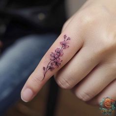 a woman's hand with a small flower tattoo on it