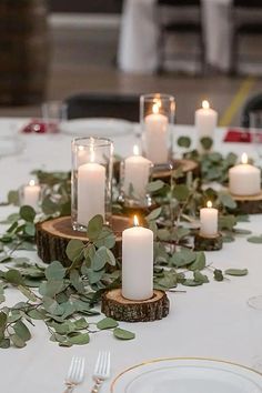 a table topped with lots of candles and greenery