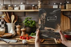 a person holding up a cookbook in front of a table full of cooking utensils