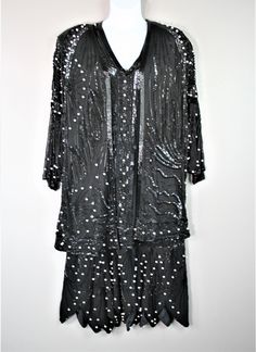 "Fantastic set!  It is in an Art Deco/Gatsby style with a duster/over jacket that features a dramatic batwing sleeve .  Both pieced are covered with geometric beading patterns accented with pearls.  They are in good to excellent vintage condition and are without holes, stains, or tearsonly about 3-5 tubular beads missing on the neckline. (pic).  We believe this to be by the label Judith Ann, based on a \"sister \" garment in pink that we had in inventory.  This garment is silk. Estimated size L/XL Sheath: 44\" total bust 40\" waist 42\" hip 48\" shoulder to hem  Purveyor's Note: We have searched far and wide, wrestled bears, braved the cold, traversed mountain ranges, fought pirates, swam with sharks and eaten at many a questionable road side taco stand to provide our customers with one of Elegant Black Sets For Costume Party, Festive Beaded Party Sets, Embellished Black Sets For Night Out, Black Embellished Sets For Night Out, Glamorous Black Embellished Set, Geometric Beading, Gatsby Art, Over Jacket, Gatsby Style