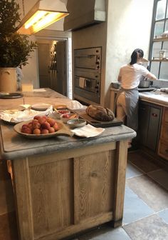 a woman standing in a kitchen preparing food on top of a wooden counter next to an oven