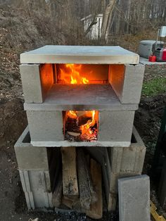 an outdoor oven with fire coming out of it's door and wood burning inside