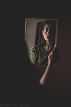 a woman is looking in the mirror and holding her hand up to her face,