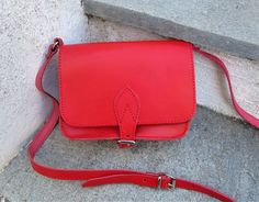 Saddle bag made from real cowhide leather in a bright red color.  Handmade in Greece. This bag has two inner compartments with a zippered pocket under the flap and features an adjustable leather strap and buckle closure. Stored and remained unused since it was made this purse is in excellent condition free from wear. Suitable for essential items such as a wallet, lipstick, keys and smart phone. Please see dimensions below. HEIGHT: 12cm (4.7 inches) WIDTH: 18cm (7 inches)  DEPTH: 6cm (2.3 inches) Leather Saddle Bags, Vintage Bags, Red Color, Cowhide Leather, Saddle Bags, Cross Body Handbags, Bag Making, Purses And Handbags, Leather Straps