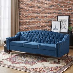 a blue couch sitting on top of a rug in front of a brick wall next to a window