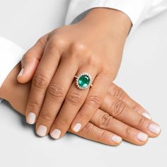 a woman's hand holding an emerald ring