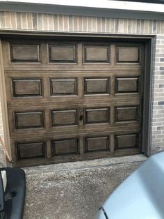 a brown garage door sitting on the side of a brick wall next to a car