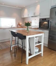 a kitchen with white cabinets and an island in front of a stove top oven next to a refrigerator