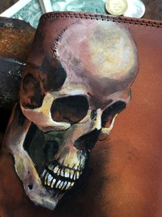 a leather wallet with a skull painted on it