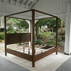 a wooden bed frame sitting on top of a white carpeted floor next to trees