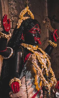 the statue is dressed in black and white with beads on it's neck, hands and feet