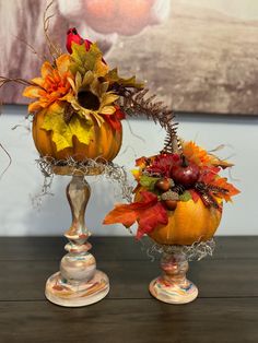 two pumpkins decorated with flowers and leaves on top of a table