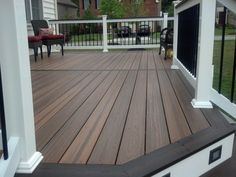 a wooden deck with white railings and black gated in area next to the house