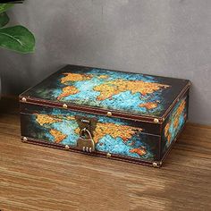 a wooden box with a world map painted on it and a plant next to it