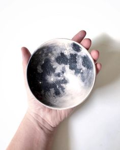 a hand holding a small bowl with the moon in it