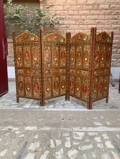 an ornately decorated room divider in front of a brick wall with a potted plant