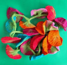 a pile of colorful felt flowers on a green background