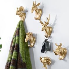 gold deer head hooks hang on a white wall next to a towel and key holder