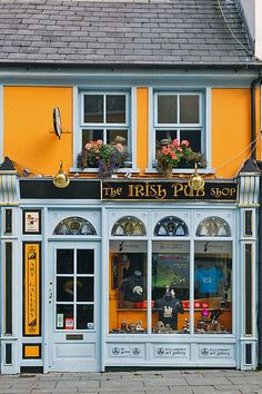 the irish pub shop is painted yellow and blue with flowers on it's windows