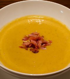 a white bowl filled with soup on top of a wooden table