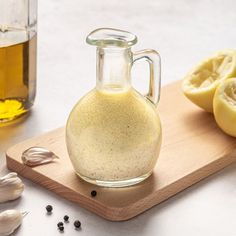 a glass bottle filled with liquid sitting on top of a cutting board next to garlic