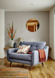 a living room with a couch, table and mirror on the wall next to it