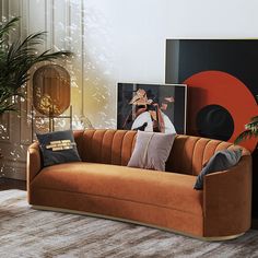 a living room with an orange couch and pictures on the wall above it, along with two potted plants