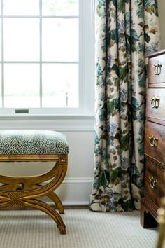 a chair sitting in front of a window next to a dresser with drawers on it