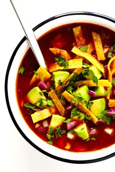 two bowls of soup with avocado, red onion and tortilla chips