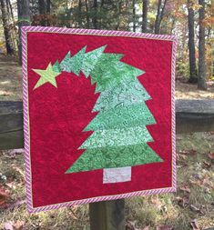 a red and green christmas tree quilted on a fence post