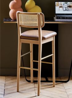 a wooden bar stool sitting next to a desk with a computer on top of it