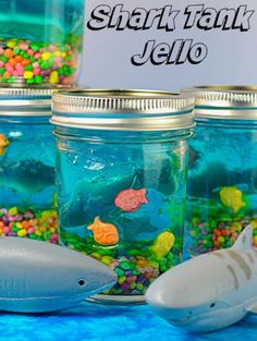 there are many fish in the jar on the table and one shark is next to it