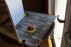 a bowl of ice cream sitting on top of a wooden table next to a window