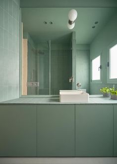 a bathroom with green walls and tile flooring, along with a white counter top