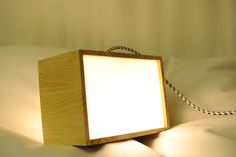 a wooden box with a white light on it sitting on a bed next to a rope