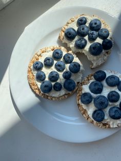 three blueberry cheesecakes on a white plate with fresh blueberries in the middle