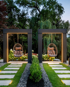 two hanging chairs in the middle of a garden with grass and stepping stones on either side