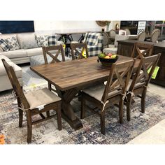 a wooden table with chairs and a bowl of fruit on it in front of couches